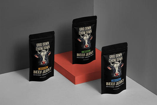 Three packages of Grid Down Chow Down beef jerky on a gray and red background